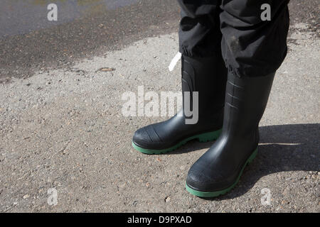 Samstag, 22. Juni 2013. Brandneue Gummistiefel mit Vertrieb Tag getragen von einer Calgary Frau auf einem Parkplatz stehen, als sie Bereinigung eines überfluteten Mehrfamilienhauses im Stadtteil Sunnyside von Calgary, Alberta, Kanada beginnt. Schwere Regenfälle schwere Überschwemmungen verursacht und führte zur Ausrufung der Notfall, obligatorische Evakuierung für den Kern der Innenstadt und vielen Wohngebieten, Stromausfälle und Sachschäden führen. Stockfoto