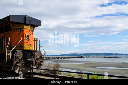 Zug-Lokomotive Umzug entlang der BNSF Bahnlinie, die den Strand in White Rock, BC, Kanada folgt. Auch Pier im Boundary Bay. Stockfoto