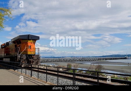 Bahn Lok Rumpeln BNSF Railway Linie, die den Strand in White Rock, BC, Kanada folgt. Auch Pier im Boundary Bay Stockfoto