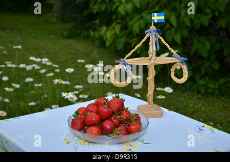Ein Teller mit frischen Erdbeeren und Dekoration im Garten am Mittsommer in Schweden. Stockfoto