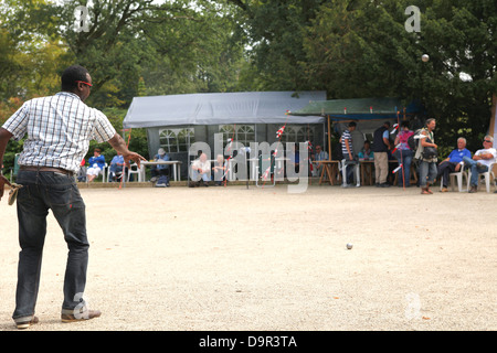 Man wirft eine Stahlkugel auf ein Petanque-Platz mit Sand während eines Wettkampfes in den Niederlanden Stockfoto