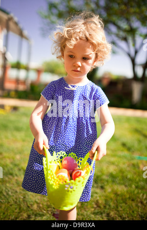 Kleines Mädchen auf ein Easter Egg hunt auf einer Wiese im Frühling Stockfoto