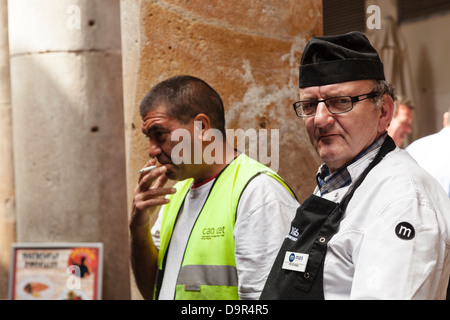 Handwerker, die eine Zigarettenpause an La Boqueria Markt Barcelona Stockfoto