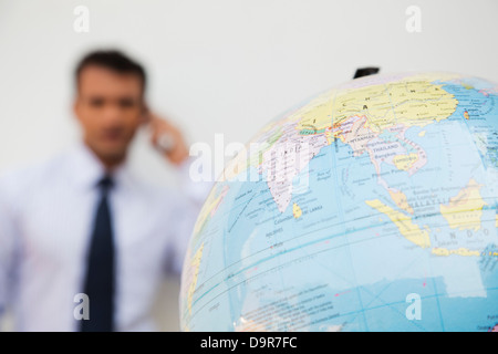 Nahaufnahme eines Globus mit einem Geschäftsmann im Hintergrund Stockfoto