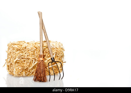 Heuballen mit Werkzeugen auf weißem Hintergrund Stockfoto