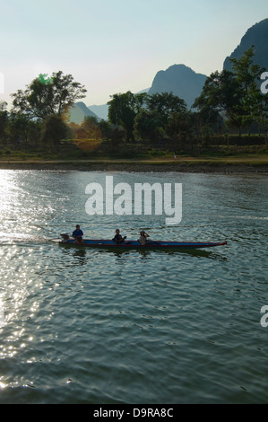 Vertikale Ansicht eines Motorbootes auf dem Nam Song River in Vang Vieng bei Sonnenuntergang unterwegs. Stockfoto