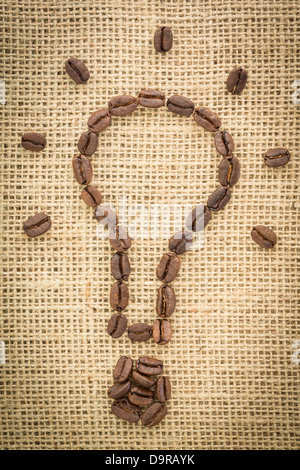 Glühbirne, gemacht aus Kaffeebohnen mit Lichtstrahlen Stockfoto