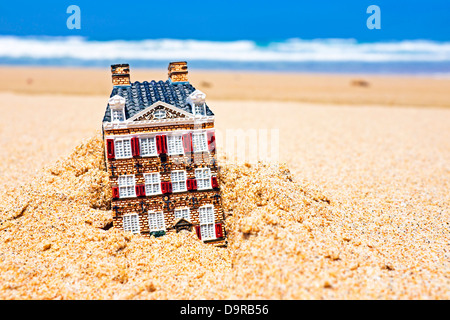 Haus im Sand verschwinden. Konzept für Immobilien in der Krise-Zeit Stockfoto