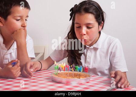 Junges Mädchen bläst-Out Kerzen auf einem Geburtstagskuchen Stockfoto