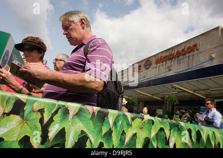 Wimbledon, England, 25. Juni 2013 - Tag2 der jährlichen Lawn Tennis Championships und Zuschauer Warteschlange für Busse außerhalb der Hauptstrecke und Underground (u-Bahn) Station in dem südlichen Vorort von London. Der Wimbledon Championships, das älteste Tennisturnier der Welt, haben seit 1877 an der nahe gelegenen All England Club statt. Stockfoto