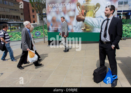 Wimbledon, England, 25. Juni 2013 - Tag2 der Zuschauer und der jährlichen Lawn Tennis Championships mischen sich mit Einheimischen in der Nähe einer großen Champions Trophy Plakatwand, außerhalb der Hauptstrecke und Underground (u-Bahn) Station in den südlichen Vorort von London. Der Wimbledon Championships, das älteste Tennisturnier der Welt, haben seit 1877 an der nahe gelegenen All England Club statt. Stockfoto