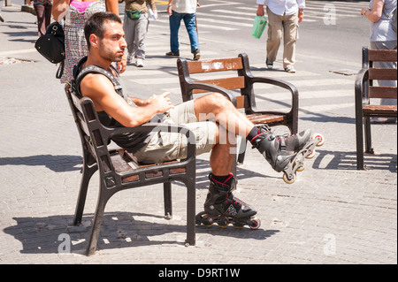 Israel Tel Aviv Jaffa Jaffa robuste junge Mann Bart rollerblade bladerunner Roller Blade Runner sitzt street scene Bank sun Gehweg Pflaster Menschen Stockfoto