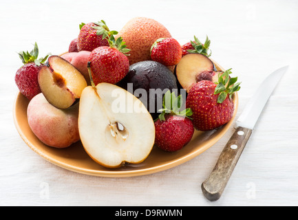 Frische Sommerfrüchte in Platte über hellen Hintergrund mit Messer, selektiven Fokus Stockfoto