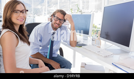 Designer sitzen an ihrem Schreibtisch und lächelt in die Kamera Stockfoto