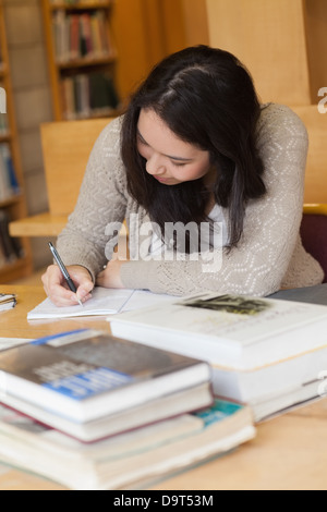 Schüler sitzen in einer Bibliothek an einem Schreibtisch und einem Schreiben Stockfoto