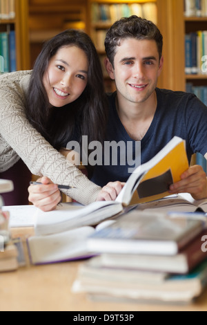 Zwei Studenten, die an einem Schreibtisch in einer Bibliothek Stockfoto