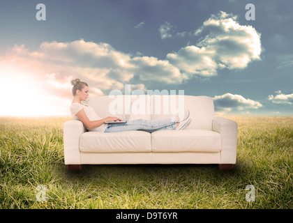 Frau mit Laptop auf der Couch im Feld Stockfoto