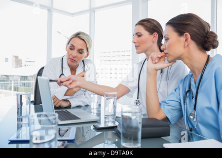 Arzt zeigen etwas auf einem Laptop zu ihren Kollegen Stockfoto