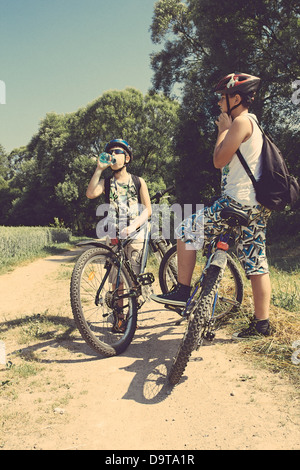 Zwei Jugendliche mit Fahrrädern entspannend auf einer Radtour in sonnigen Tag, Retro-Farben Stockfoto