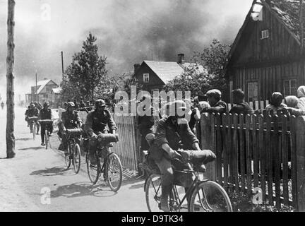 Soldaten der Fahrradtruppen fahren mit dem Fahrrad durch ein Dorf an der Ostfront, veröffentlicht am 2. Juli 1941. Ort unbekannt. Die Nazi-Propaganda! Auf der Rückseite des Bildes steht: "Die Infanterie fährt durch ein rauchiges Dorf, auf der vorausfahrenden Straße im Osten." Der Angriff des Deutschen Reiches auf Russland wurde im Juli 1940 vereinbart und seit Dezember 1940 als "Operation Barbarossa" vorbereitet. Am 22. Juni 1941 begann die Invasion der Sowjetunion durch die deutsche Wehrmacht. Fotoarchiv für Zeitgeschichte Stockfoto