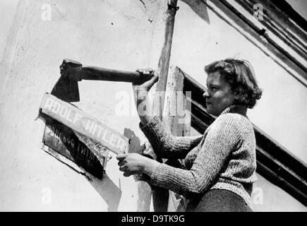 Eine Frau entfernt am Ende des Zweiten Weltkriegs das Straßenschild einer Straße, die in „Adolf Hitler“ umbenannt wurde und das ursprüngliche Straßenschild mit russischen Buchstaben enthüllt Datum und Ort unbekannt. Fotoarchiv für Zeitgeschichte Stockfoto