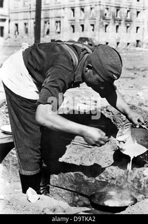 Die Originalfotografie, aus der dieses digitale Bild gemacht wurde, liest auf dem Rücken die nationalsozialistische Propaganda vom 22. Oktober 1942: "Pfannkuchen an einem Bahnhof in Stalingrad. Der Koch einer Flak-Batterie bereitet das Mittagessen zu - heute sind es Pfannkuchen.“ Fotoarchiv für Zeitgeschichte Stockfoto