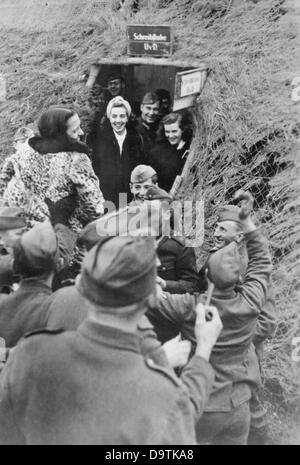 Soldaten sind mit Schauspielerinnen einer Theatergruppe an der Ostfront, veröffentlicht 29. Februar 1944 abgebildet. Der NS-Propaganda! auf der Rückseite des Bildes liest: "Varieté-Show im Bunker. Die Ankunft der Schauspielerinnen einer vorderen Theatergruppe, die die "Spiess" (The Spear - Spitzname für die Company Sergeant Major) angekündigt. Voller Vorfreude, die Soldaten Menschenmenge zusammen vor der Batterie Bunker, Tänzerin und Sängerin auf ihren Schultern in Richtung der Bunker zu tragen. Mit humorvollen schreien, beweisen die Männer ihre Freude über die angenehme Unterbrechung der täglichen Pflicht. " Foto: Berliner Verlag/Ar Stockfoto