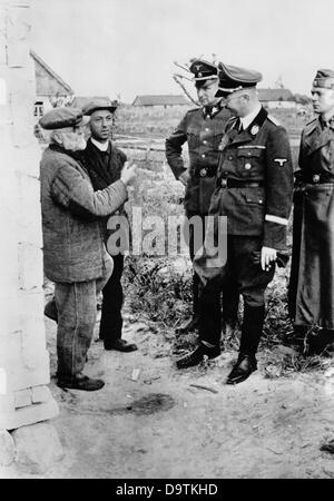 Feldmarschall der SS und Chef der deutschen Polizei, Heinrich Himmler, spricht mit Einheimischen an der Ostfront. Die Nazi-Propaganda! Auf der Rückseite des Bildes ist vom 26. November 1941 datiert: "Reichsführer der SS und Chef der deutschen Polizei Heinrich Himmler unterzog sich einer Inspektion an der Ostfront. In einem deutschen Dorf im sowjetischen Gebiet hielt er an und sprach intensiv mit den Dorfbewohnern über ihr Leid unter dem grauenhaften Joch des Bolschewismus." Fotoarchiv für Zeitgeschichte Stockfoto