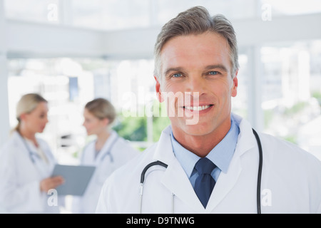 Lächelnde grauen Haaren Arzt in seinem Büro stehen Stockfoto