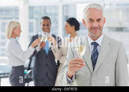 Geschäftsmann lächelnd in die Kamera hält Champagner Stockfoto