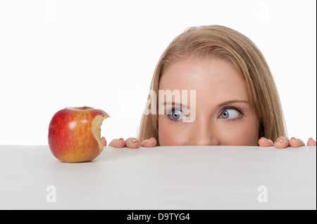 Nahaufnahme der jungen Frau, die Hälfte gegessen Apfel - humorvolle Diät oder Versuchung Konzept betrachten Stockfoto