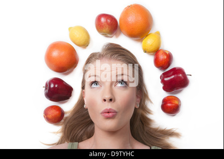 Nette junge Frau, umgeben von Obst - gesunde Ernährung Konzept, isoliert auf weiss Stockfoto