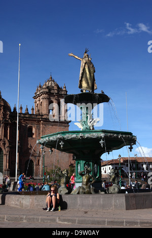 Touristen sitzen neben Brunnen mit Statue von Pachacútec Inca Yupanqui oder Pachacutec, Kathedrale im Hintergrund, Cusco, Peru Stockfoto