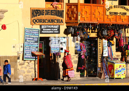 Einheimische einheimische Quechua-Dame in traditioneller Kleidung, vorbei an Souvenirladen und Cafés, Ollantaytambo, Heiliges Tal, in der Nähe von Cusco, Peru Stockfoto