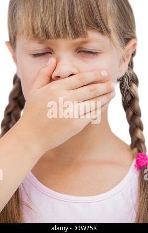 Kleines blondes Mädchen mit der Hand auf den Mund mit ihren Augen geschlossen Stockfoto