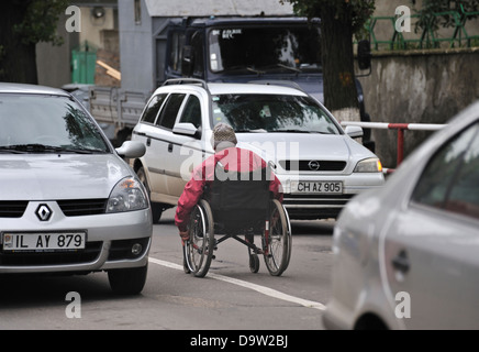 Mann im Rollstuhl betteln unter Autos warten auf die Ampel zu verändern, Chisinau, Moldawien Stockfoto
