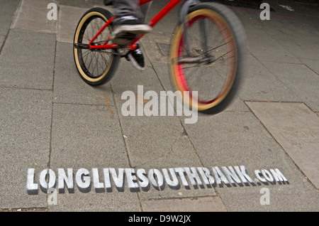 Ein BMX-Fahrer springt über eine Schablone, die Werbung der Website-Url-longlivesouthbank.com. Stockfoto