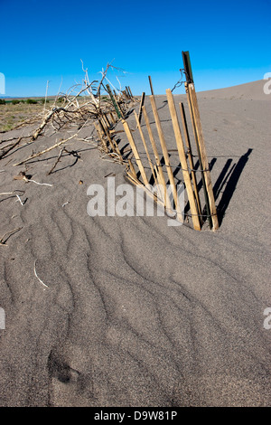 Ein alten Zaun ist teilweise in den Sand im Bruneau Dunes State Park beigesetzt. Stockfoto