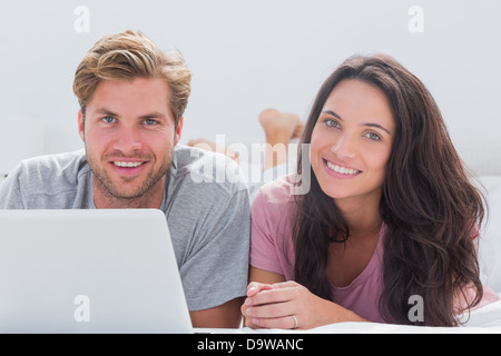 Fröhliches paar mit Laptop im Bett Stockfoto