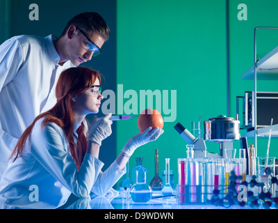 zwei Wissenschaftler, die Durchführung eines Experiments auf einer Grapefruit in einem Labor Stockfoto