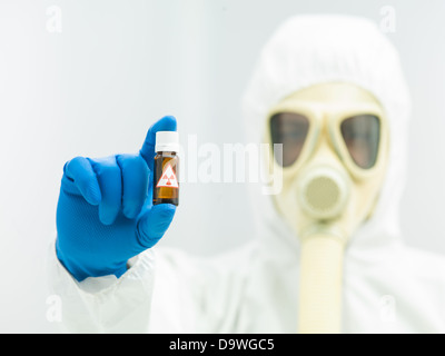 Radioaktives Isotop Probe in einer kleinen braunen Flasche mit einem Warnhinweis statt in den Fingern ein Labor Wissenschaftler in Schutzkleidung mit einer Maske und Atmung-Apparat Stockfoto