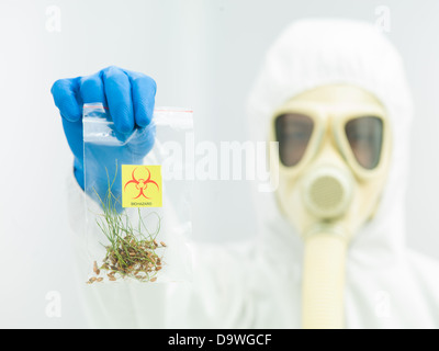 Person im Schutzanzug und Gasmaske hält eine Tasche mit einer Stichprobe von kontaminierten Ernte Stockfoto