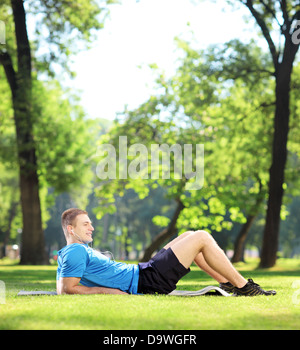 Junge Sportler liegen auf einer Matte in einem park Stockfoto