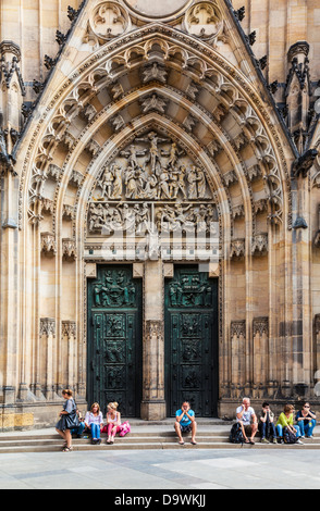 Touristen sitzen vor der mittelalterlichen gotischen Fassade von St Vitus Cathedral in Prag. Stockfoto