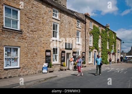 Menschen Touristen Besucher zu Fuß rund um den Marktplatz im Sommer Masham Wensleydale North Yorkshire Dales England Vereinigtes Königreich GB Großbritannien Stockfoto