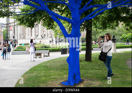 London, UK. 27. Juni 2013. Festival-Gärten, City of London. Menschen interagieren Sie mit einer der Bäume, die als Teil der blauen Bäume in London Kunstinstallation blau gemalt. Nächstenliebe Bäume für Städte gemeinsam mit internationalen Künstler, Konstantin Dimopoulos, kam mit dem Blue Tree-Konzept. Die Idee des Projekts ist es, Menschen zu stoppen und beachten Sie die Bäume im städtischen Umfeld. Wenn Stadtbevölkerung wächst, verringert sich die Anzahl der Bäume in der Stadt. Aber viele Menschen heute um zu betrachten, berühren und Foto eines der blauen Bäume gestoppt. Bildnachweis: Allsorts Stock Foto/Alamy Live-Nachrichten Stockfoto