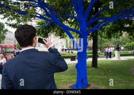 London, UK. 27. Juni 2013. Festival-Gärten, City of London. Menschen interagieren Sie mit einer der Bäume, die als Teil der blauen Bäume in London Kunstinstallation blau gemalt. Nächstenliebe Bäume für Städte gemeinsam mit internationalen Künstler, Konstantin Dimopoulos, kam mit dem Blue Tree-Konzept. Die Idee des Projekts ist es, Menschen zu stoppen und beachten Sie die Bäume im städtischen Umfeld. Wenn Stadtbevölkerung wächst, verringert sich die Anzahl der Bäume in der Stadt. Aber viele Menschen heute um zu betrachten, berühren und Foto eines der blauen Bäume gestoppt. Bildnachweis: Allsorts Stock Foto/Alamy Live-Nachrichten Stockfoto