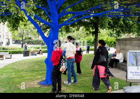 London, UK. 27. Juni 2013. Festival-Gärten, City of London. Menschen interagieren Sie mit einer der Bäume, die als Teil der blauen Bäume in London Kunstinstallation blau gemalt. Nächstenliebe Bäume für Städte gemeinsam mit internationalen Künstler, Konstantin Dimopoulos, kam mit dem Blue Tree-Konzept. Die Idee des Projekts ist es, Menschen zu stoppen und beachten Sie die Bäume im städtischen Umfeld. Wenn Stadtbevölkerung wächst, verringert sich die Anzahl der Bäume in der Stadt. Aber viele Menschen heute um zu betrachten, berühren und Foto eines der blauen Bäume gestoppt. Bildnachweis: Allsorts Stock Foto/Alamy Live-Nachrichten Stockfoto