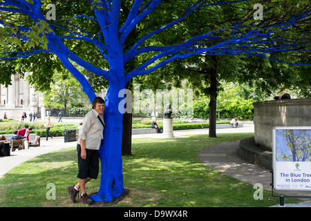 London, UK. 27. Juni 2013. Festival-Gärten, City of London. Menschen interagieren Sie mit einer der Bäume, die als Teil der blauen Bäume in London Kunstinstallation blau gemalt. Nächstenliebe Bäume für Städte gemeinsam mit internationalen Künstler, Konstantin Dimopoulos, kam mit dem Blue Tree-Konzept. Die Idee des Projekts ist es, Menschen zu stoppen und beachten Sie die Bäume im städtischen Umfeld. Wenn Stadtbevölkerung wächst, verringert sich die Anzahl der Bäume in der Stadt. Aber viele Menschen heute um zu betrachten, berühren und Foto eines der blauen Bäume gestoppt. Bildnachweis: Allsorts Stock Foto/Alamy Live-Nachrichten Stockfoto