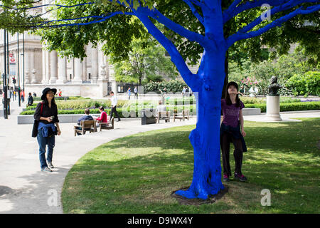 London, UK. 27. Juni 2013. Festival-Gärten, City of London. Menschen interagieren Sie mit einer der Bäume, die als Teil der blauen Bäume in London Kunstinstallation blau gemalt. Nächstenliebe Bäume für Städte gemeinsam mit internationalen Künstler, Konstantin Dimopoulos, kam mit dem Blue Tree-Konzept. Die Idee des Projekts ist es, Menschen zu stoppen und beachten Sie die Bäume im städtischen Umfeld. Wenn Stadtbevölkerung wächst, verringert sich die Anzahl der Bäume in der Stadt. Aber viele Menschen heute um zu betrachten, berühren und Foto eines der blauen Bäume gestoppt. Bildnachweis: Allsorts Stock Foto/Alamy Live-Nachrichten Stockfoto